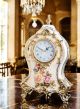 Reloj de mesa en refinada cerámica, con elegantes detalles florales y dorados, elaborado artesanalmente.